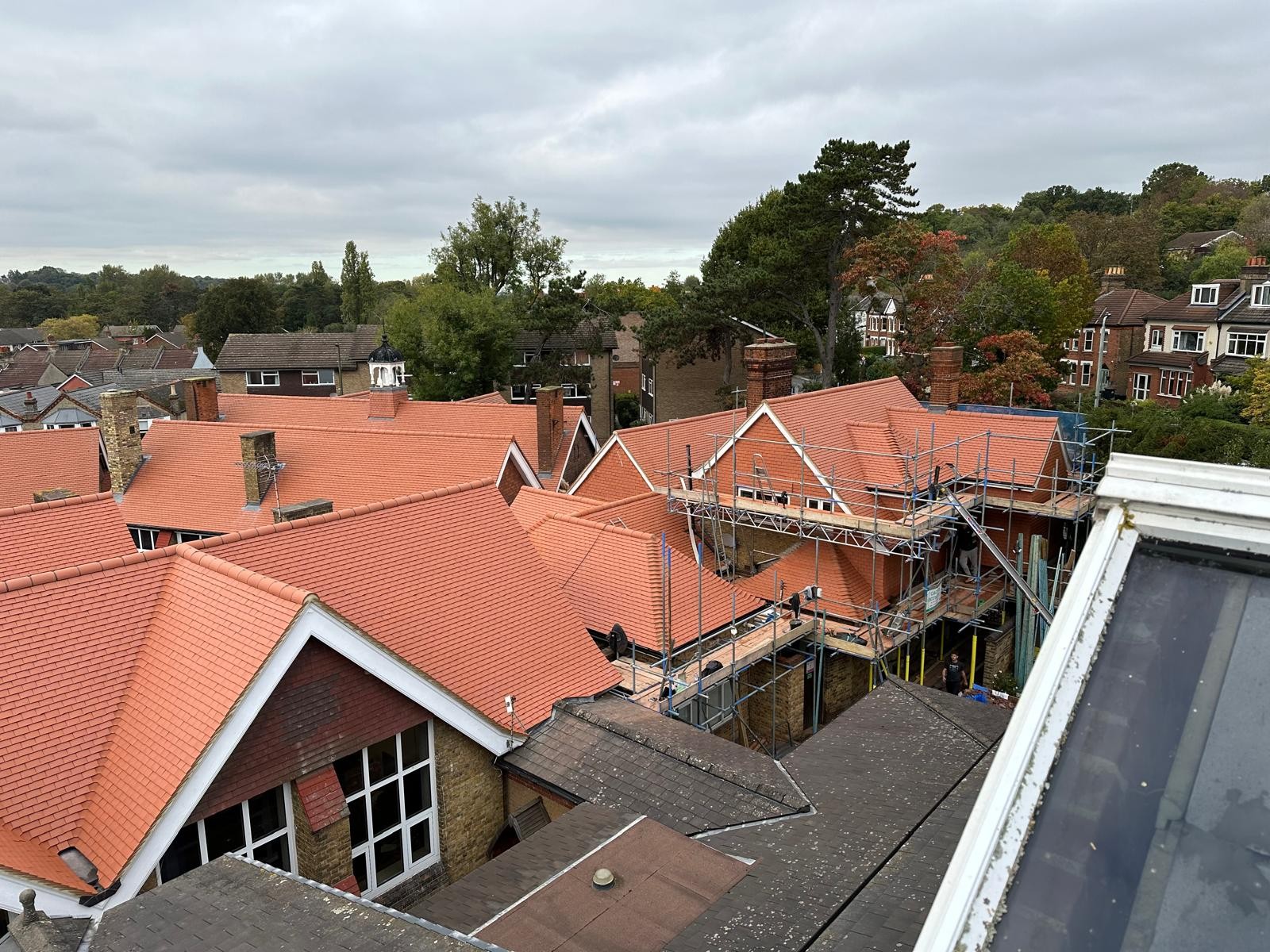 Home - Completed CIF-funded school roof replacement with new red tiles and scaffolding during final refurbishment works.
