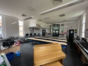 Modern school classroom with desks, computers, and piano for music lessons.