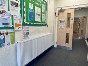 School corridor with noticeboard and fire door.