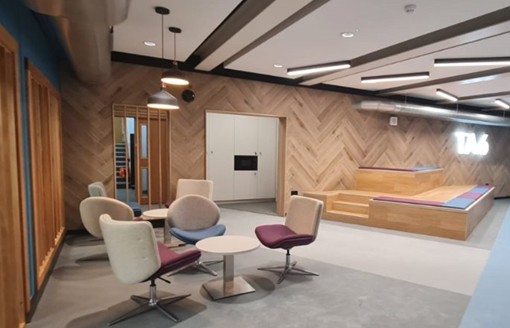 Modern interior design of a collaborative workspace with stylish seating, wood-panelled walls, and contemporary lighting.