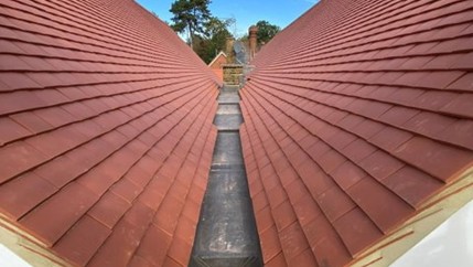 Red tiled pitched roof with central gutter.