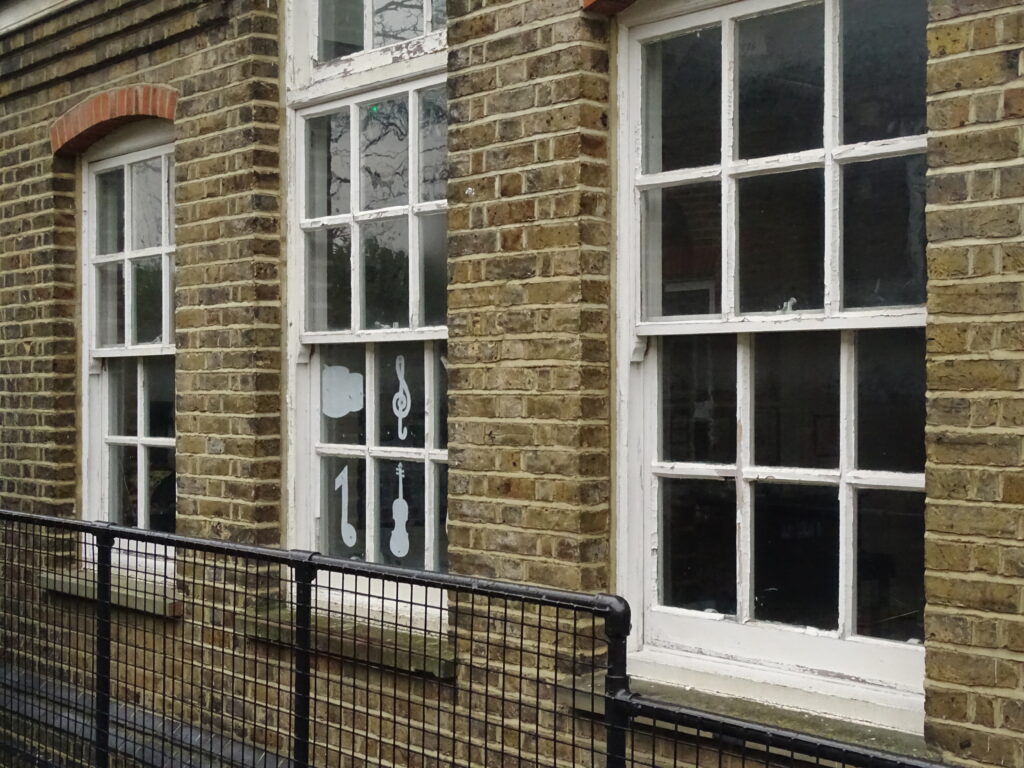 Condition survey photo showing deteriorating timber-framed school windows with peeling paint, highlighting the need for refurbishment or replacement.