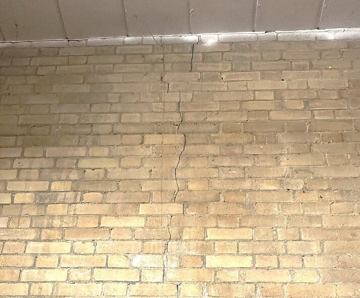 Condition survey photo showing structural crack in brick wall, highlighting the need for urgent inspection and building maintenance.