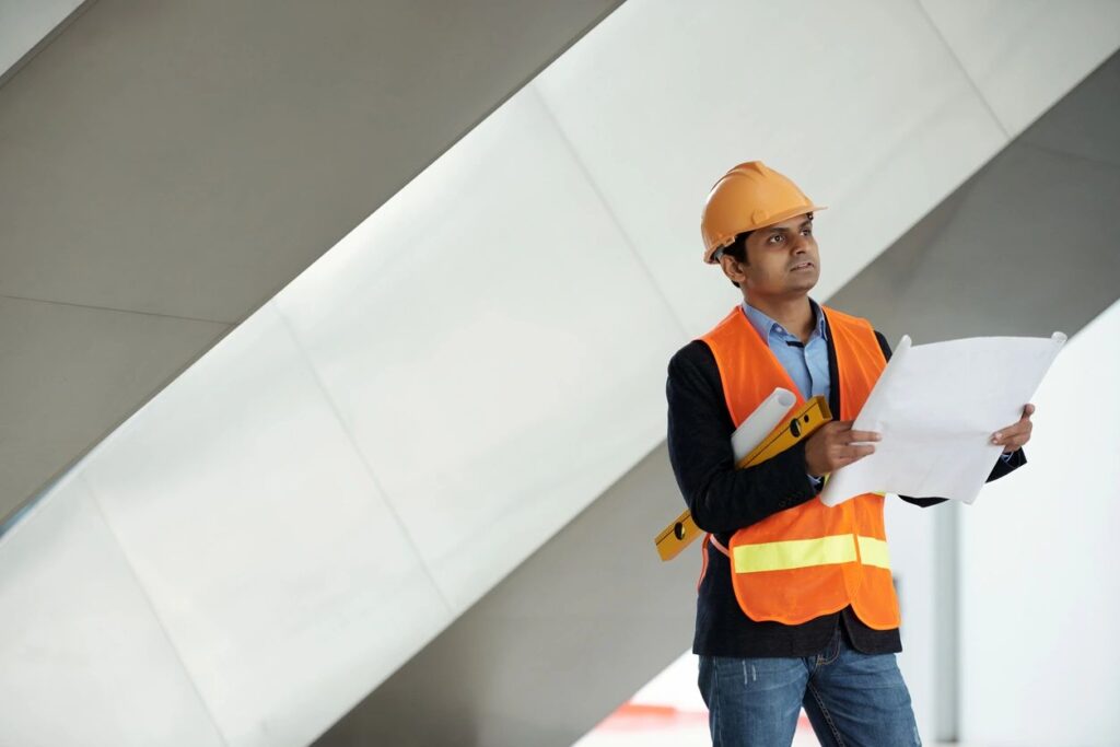 Construction consultant conducting a site inspection with building plans, supporting condition surveys and project assessments.
