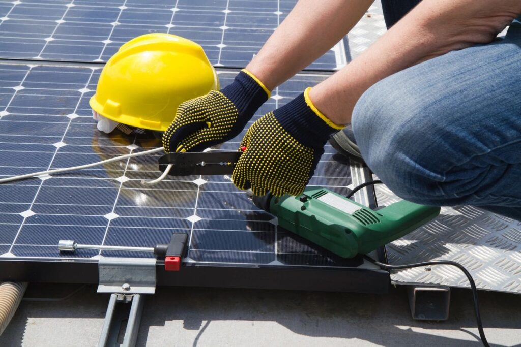 Engineer installing solar panels with protective gloves and safety helmet, promoting renewable energy and sustainable school refurbishment.