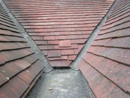 Close-up of damaged school roof valley showing slipped tiles identified in condition survey before CIF-funded replacement.