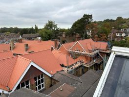 Home - Completed CIF-funded school roof replacement with new red tiles and scaffolding during final refurbishment works.