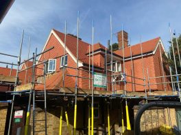 CIF-funded school roof replacement in progress with scaffolding around newly tiled building.