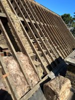 School roof stripped back to rafters during CIF-funded replacement project with insulation materials prepared for installation.