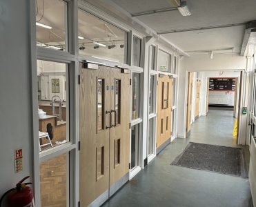 School corridor with newly installed fire safety doors and reinforced glass panels, enhancing security and compliance.