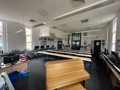 Modern school classroom with desks, computers, and piano for music lessons.