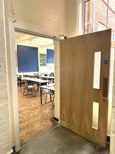 CIF-funded school refurbishment showing new classroom fire door installation and improved learning space.