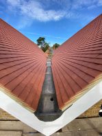 Completed school roof valley with new red tiles and leadwork installed during CIF-funded replacement project.