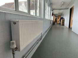 CIF-funded school heating upgrade with new energy-efficient radiator installation in corridor.