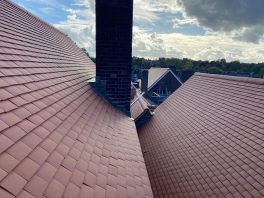 Completed school roof replacement around chimney with new red tiles installed through CIF-funded refurbishment project.