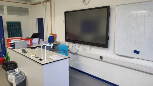 Modern science lab with interactive whiteboard, teacher’s desk, and wall-mounted services.