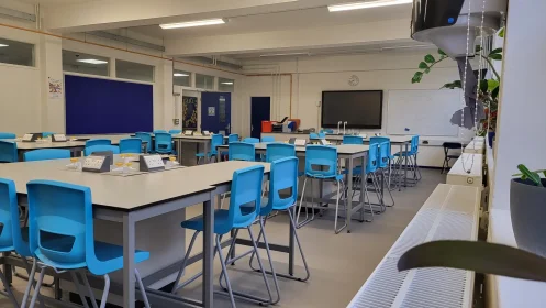 Clean, modern lab space with high stools, digital teaching board, whiteboard, and visible utility pipework.
