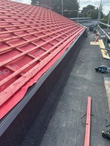External view of pitched roof in progress with waterproof membrane and red battens installed, ready for tile application.