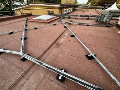 Case Studies - Flat roof covered in newly installed red mineral felt, surrounded by scaffolding for safety during construction.