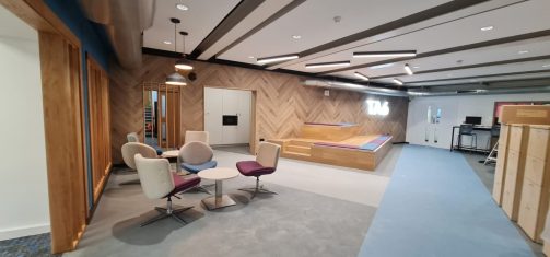 Contemporary student social and study space with comfortable seating, TA6 signage, and modern lighting.