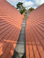 Completed school roof valley with new red tiles and leadwork installed under CIF-funded replacement project.